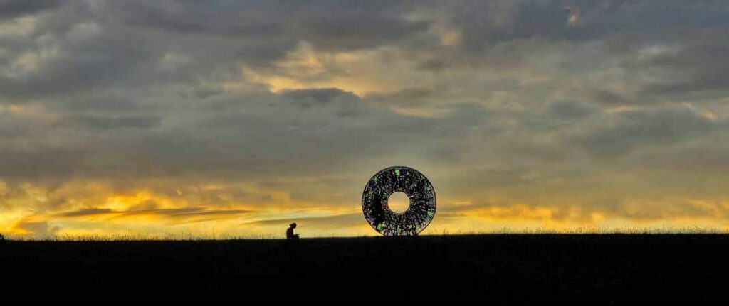 AIRIS als Silhouette im Sonnenuntergang in Zierenberg, daneben eine sitzende Person