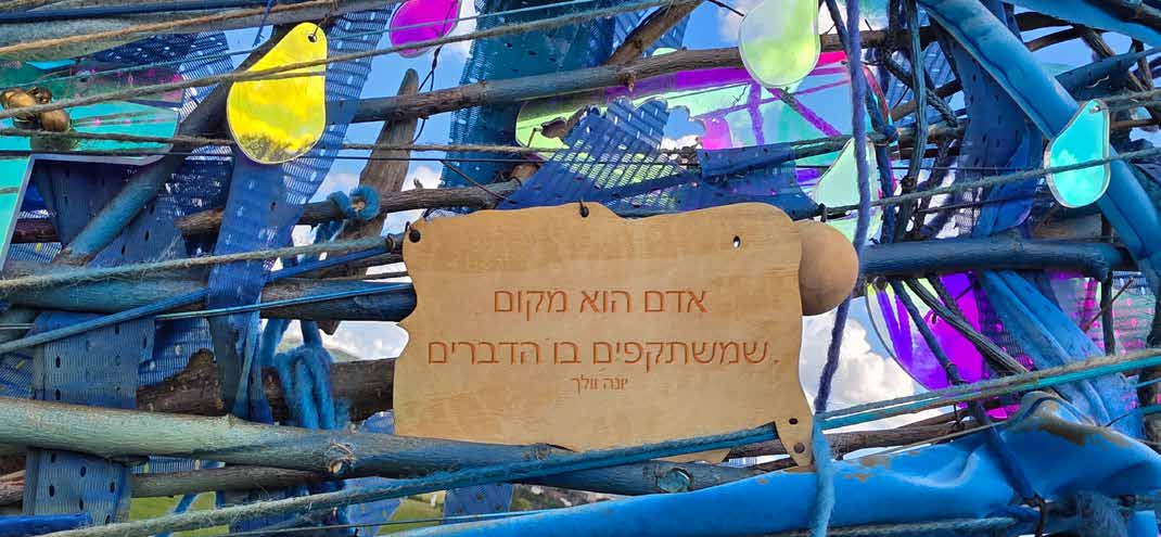 Holzplakette mit hebräischer Inschrift zwischen blauen Stoffstreifen