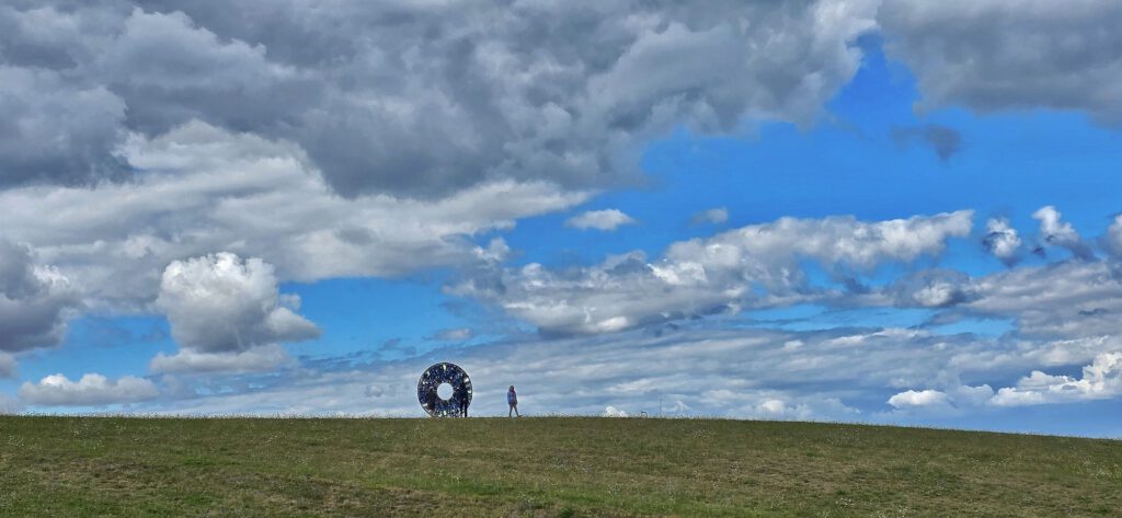 AIRIS auf dem Hügel, Besucher unter weitem Wolkenhimmel