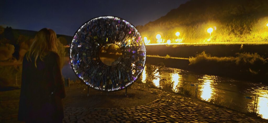 AIRIS am Weserstein bei Nacht mit Lichterkette, eine Besucherin schaut zu