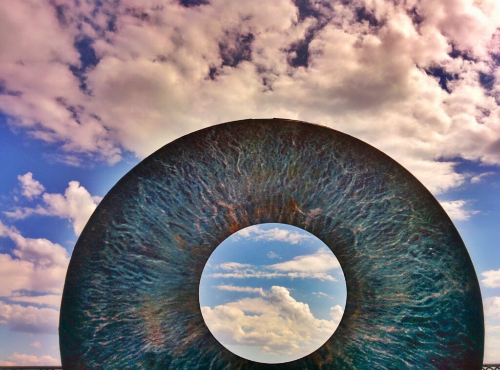 IRIDO vor Wolkenhimmel, im Auge der Himmel